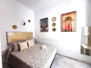 a bedroom with a bed and paintings on the wall at Budget & Lovely Rooms Las Setas in Seville