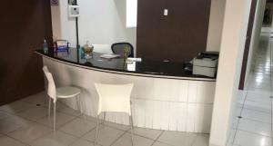 乌贝兰迪亚UDI Hostel Hospedaria的酒吧配有两把白色椅子和黑柜台