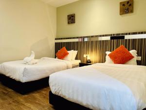 una habitación de hotel con 2 camas con un animal de peluche. en Kino Hotel, en Shah Alam