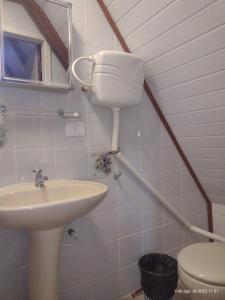 La salle de bains est pourvue d'un lavabo et de toilettes. dans l'établissement Apartamento estilo chalé - Enxaimel, à Bombinhas