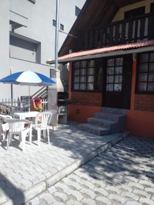 un patio con mesa, sillas y sombrilla en Apartamento estilo chalé - Enxaimel, en Bombinhas