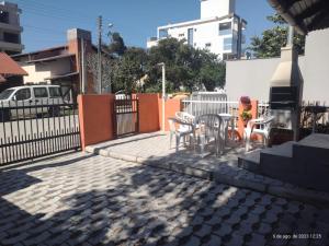 a patio with a table and chairs and a fence at Apartamento estilo chalé - Enxaimel in Bombinhas