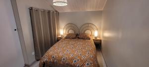 a bed in a bedroom with two tables and two lamps at La p'tite maison in Londinières