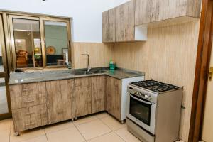 a kitchen with wooden cabinets and a stove and a sink at Home with Swimingpool in Kigali