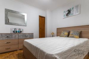 um quarto com uma cama, uma cómoda e um espelho em Cantinho dos Avós em Viana do Castelo