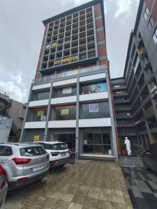 a large building with cars parked in front of it at Hotel Prime Villa Gurukul in Ahmedabad