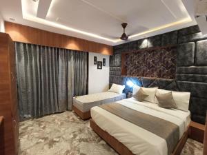 a bedroom with two beds and a stone wall at Hotel Prime Villa Gurukul in Ahmedabad