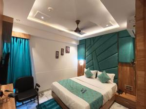 Hotel Prime Villa Gurukul في أحمد آباد: غرفة نوم بسرير على اللوح الاخضر وكرسي