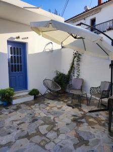 a patio with chairs and an umbrella and a blue door at Giorgio studios in Kokkari