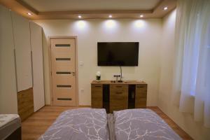 a bedroom with a flat screen tv on the wall at Kinder Apartman in Makó
