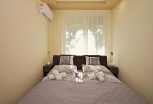 1 dormitorio con cama con almohadas y ventana en Kinder Apartman, en Makó
