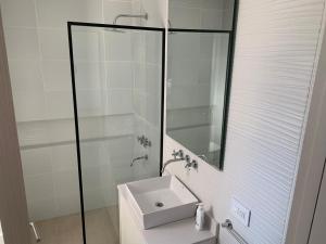 Un baño blanco con lavabo y espejo. en Dpto Bastion del Este 103, en Tandil 6 fotos más