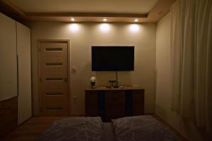 a bedroom with a flat screen tv on the wall at Kinder Apartman in Makó