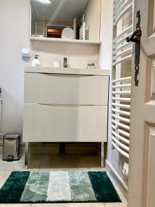 La salle de bains est pourvue d'un lavabo blanc et d'un tapis vert. dans l'établissement Gîte Maison Made in Normandie, à Bois-Normand-près-Lyre