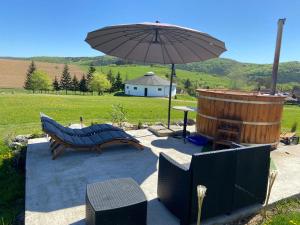 a patio with an umbrella and a bench and a barrel at Aranyló Vendégház in Alsótelekes