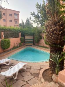 una piscina con 2 sillas y una palmera en Villa a Marrakech en Marrakech