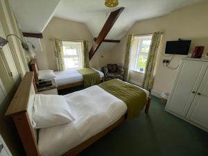 a bedroom with two beds and a tv and two windows at Maenllwyd Guest House in Machynlleth