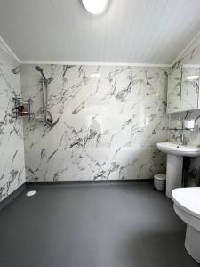 a bathroom with a sink and a white marble wall at Diddly Squat Lodge with hot tub, Pendle View Holiday Park in Clitheroe