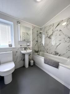 a white bathroom with a toilet and a sink at Diddly Squat Lodge with hot tub, Pendle View Holiday Park in Clitheroe