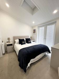 a white bedroom with a large bed and two windows at Diddly Squat Lodge with hot tub, Pendle View Holiday Park in Clitheroe