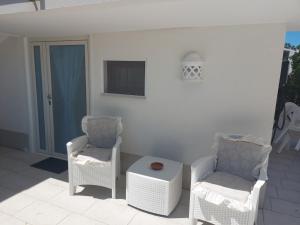 un patio con 2 sillas, TV y mesa en Casa Vacanza Fiori di Maggio, en Pulsano