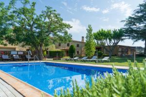 ein Swimmingpool in einem Hof mit Stühlen und Bäumen in der Unterkunft Masía Rural Can Poch in Pals