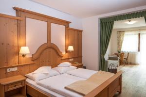 a bedroom with a large bed with a wooden headboard at Hotel Falken in Falzes