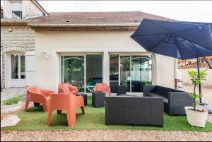 a patio with tables and chairs and an umbrella at villa grand mère marie in Brazey-en-Plaine