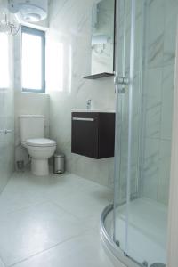 ein weißes Bad mit einer Dusche und einem WC in der Unterkunft Side-seaview apartment near beach and close to St. Julians in Baħar iċ-Ċagħaq