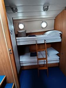 Mały pokój z 2 łóżkami piętrowymi i krzesłem w obiekcie Traditional 2 bedroom houseboat Nova Natalina w mieście Brovinje