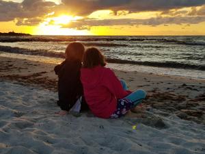 two girls sitting on the beach watching the sunset at Staberhuk Baben - großer sonniger Balkon - XL Wohnung in Staberdorf
