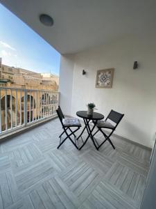 Cette chambre dispose d'un balcon avec une table et deux chaises. dans l'établissement Marsalforn luxurious Apartment, à Marsalforn