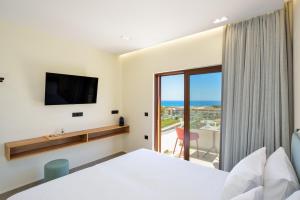 1 dormitorio con 1 cama, TV y balcón en Panthea Luxury Living en Kolymvari