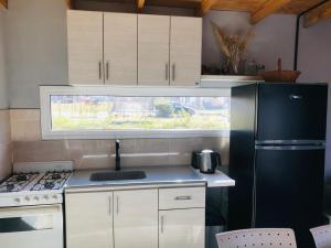a kitchen with white cabinets and a black refrigerator at Casita el Emir in Plottier