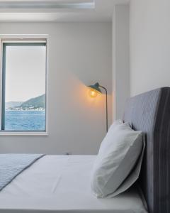 ein weißes Schlafzimmer mit einem Bett und einem Fenster in der Unterkunft Casa di Lukovic in Tivat