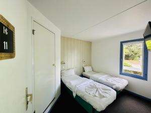 two beds in a small room with a window at Hôtel Gex in Gex