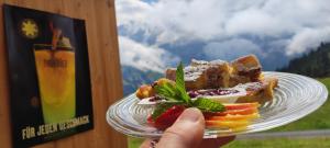 a person holding a plate with food on it at Hotel Restaurant Sonnenberg in Mürren