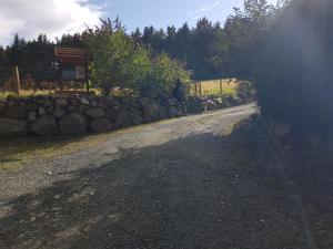 a dirt road with a stone wall next to a building at FOREST VIEW Woodland lodge in Ballard