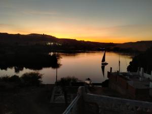 a sunset over a river with a boat in it at Seko Kato Nile View Hostel in Aswan