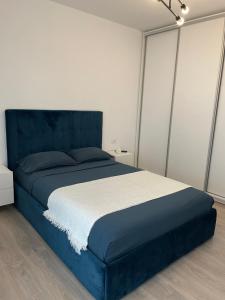 Schlafzimmer mit einem blauen Bett und einem blauen Kopfteil in der Unterkunft Luna Luxury Apartment by the Zoo in Râmnicu Vâlcea