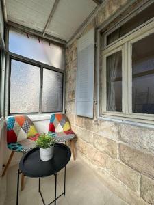 une chambre avec deux chaises, une table et deux fenêtres dans l'établissement HaMadregot 3, à Jérusalem