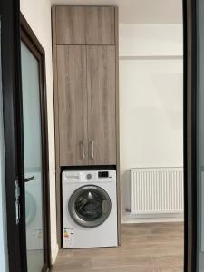 uma lavandaria com uma máquina de lavar roupa e um armário de madeira em Luna Luxury Apartment by the Zoo em Râmnicu Vâlcea
