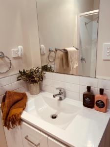 a white bathroom with a sink and a mirror at Adventure Bay Holiday Home in Adventure Bay