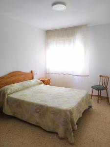 a bedroom with a bed and a chair and a window at Apartamento con vistas al mar y buena ubicación in Benicàssim
