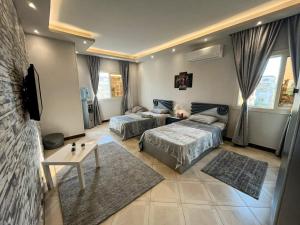 a bedroom with two beds and a table and a tv at Luxury & spacious 3BD Apartment in family house in Cairo