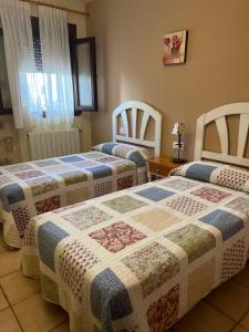 Habitación con 2 camas y mesa. en Apartamentos Los Parrales, en Villalba de la Sierra