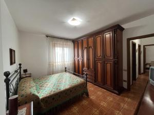 Appartamento Incantevole a Follonica Mare- 5 posti في فولونيكا: غرفة نوم بسرير وخزانات خشبية