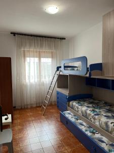 Appartamento Incantevole a Follonica Mare- 5 posti في فولونيكا: غرفة مع سرير بطابقين وسلم