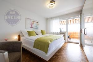 a white bedroom with a large bed and a chair at 3 Zimmer Familienwohnung mit WLAN & Netflix in Mönchengladbach