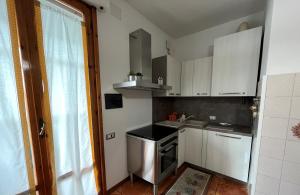 Appartamento Incantevole a Follonica Mare- 5 posti في فولونيكا: مطبخ صغير مع دواليب بيضاء وموقد